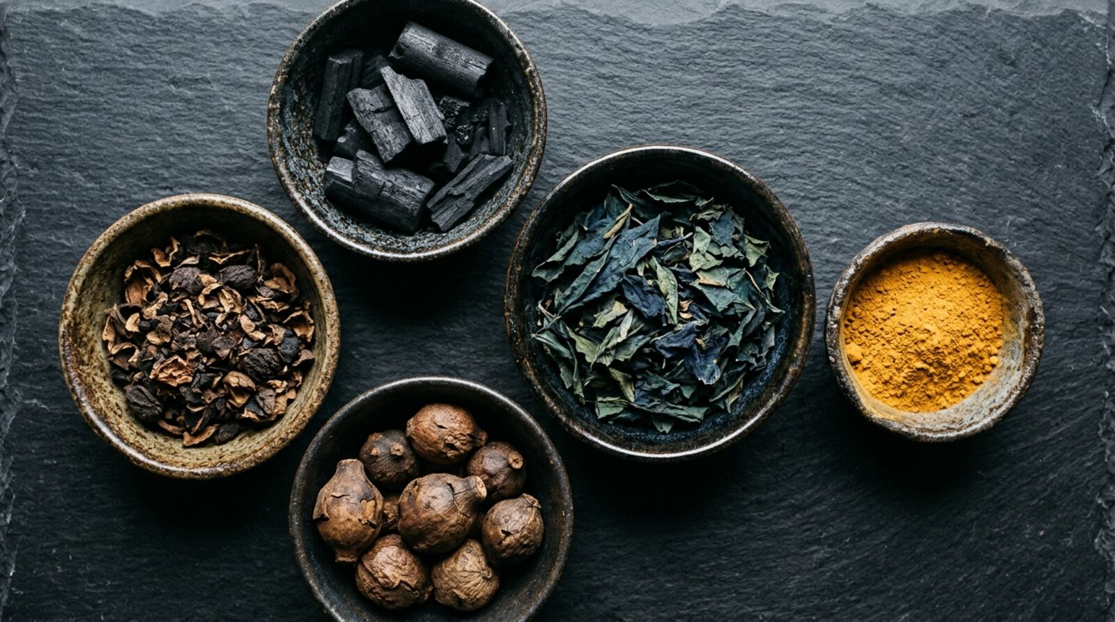 Bowls of hardwood charcoal, walnut hulls, indigo leaves, oak galls and ochre on slate